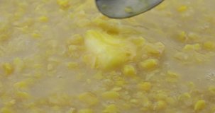 Close video of stirring a tablespoon of margarine into cream style corn with a spoon while heating.