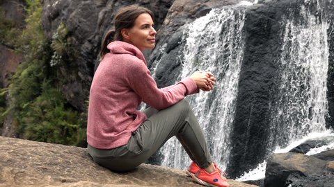 Pensive woman relaxing, sitting near waterfall, super slow motion 240fps
