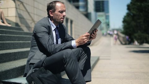 Businessman reading news on tablet computer in the city
