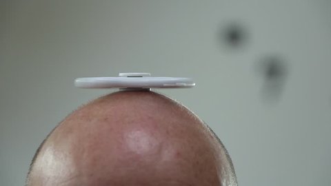Spinner on head of bald man close up