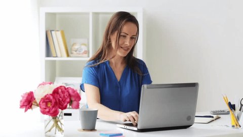business, freelance, people and technology concept - happy smiling woman with laptop computer writing to notebook at home or office