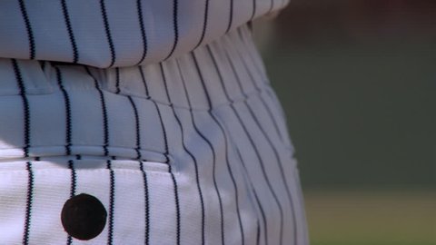 Close-up of left-handed pitcher holding ball behind his back, zoom-out to wind-up