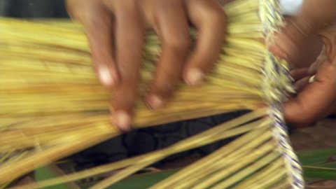 Close-up of Fijian woman's hands as she makes a broom from palm fronds