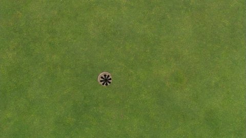 Overhead shot of hole on green and golf ball going in