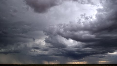 Time-lapse storm clouds driven by cross-currents as rain falls on horizon