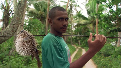 Fijian man with speared blowfish posing on jungle road