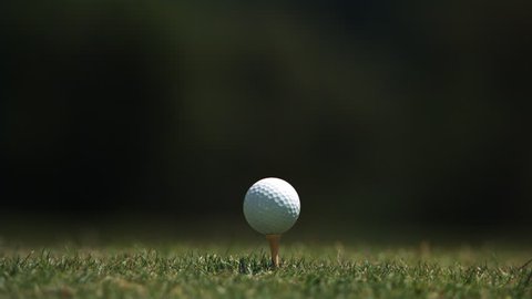 Close-up of golf ball on tee and club head striking it in ultra-slow motion