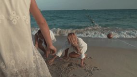 Happy mother and her daughters are painting on the sand of beach of South China Sea, Yalong Bay slow motion stock footage video