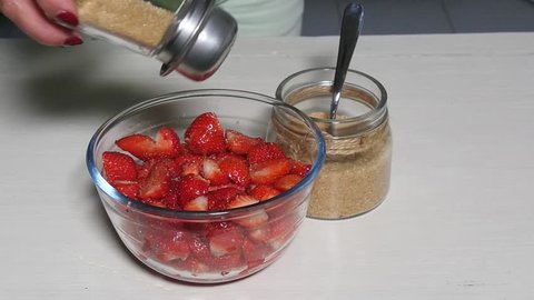 woman sprinkling sugar on the strawberries