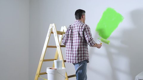 Man painting interior walls at home using a paint roller, home renovation and redecoration concept