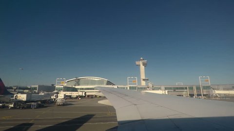 New York, USA - April 18 2017: JFK airport terminal and runway view.
John F. Kennedy International Airport inside taxiing aircraft window view of airport traffic control tower and gates.