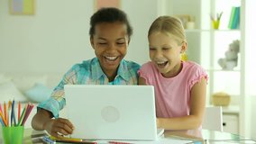 Girls laughing at funny stuff displayed on the screen of the laptop