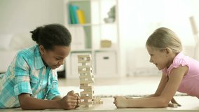 Lovely girls playing a game of risk trying to move wooden blocks without destroying the whole tower - Powered by Shutterstock - Get 15% off with code: PIKWIZARD15