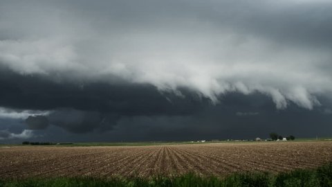 Huge shelf cloud out ahead of a cool outflow of air from a thunderstorm above prairie cropland