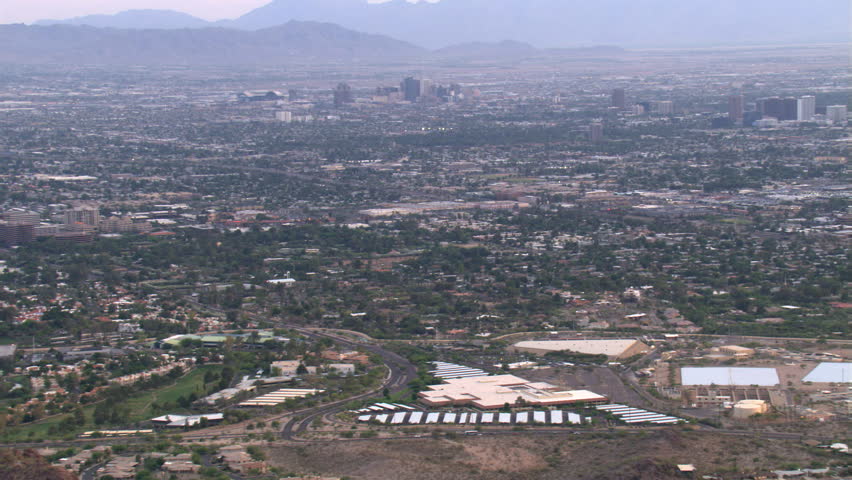 Wide view of distant downtown Phoenix and outlying areas, rocky peak through frame. Shot in 2007.