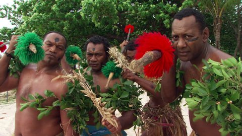 Four Fijian men with decorated spears taking part in traditional ceremony