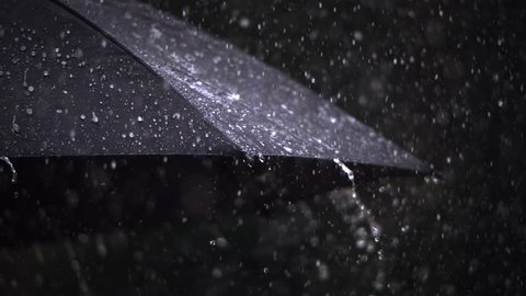 Close-up ultra-slow motion rain falling on a black umbrella
