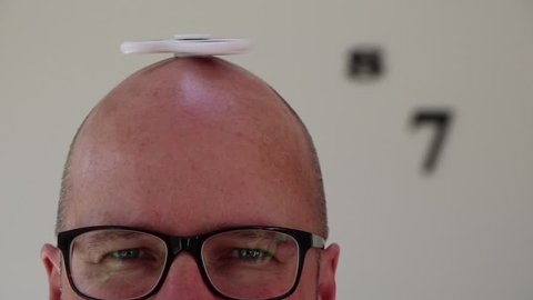 Bald man with spinning top on head