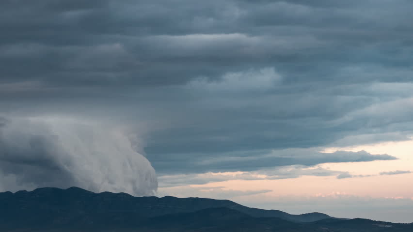 Time-lapse of spectacular clouds slithering over mountain range at dusk