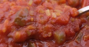 Very close video of heated chunky thick spaghetti sauce being stirred with a spoon.