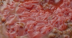 Close video of stirring ketchup into cooked bacon and onion flavored baked beans with a fork then taking a bite at the end.