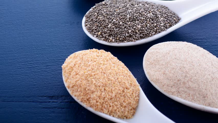High fiber nutritious grains including white grain quinoa, psyllium husk powder, black chia, wheat germ, and ground LSA mix, in measuring spoons, panning shot.  Royalty-Free Stock Footage #26667523