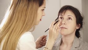 Young makeup artist applying base with brush to face