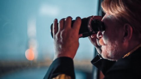 Ship captain with a binoculars looking at the river