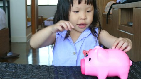 Cute little girl putting money in piggy bank 
