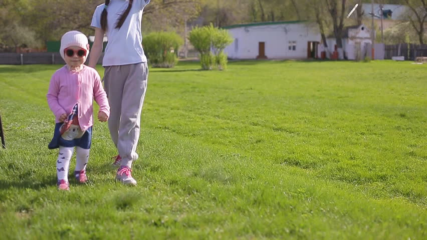 Two sisters play and run around the green grass