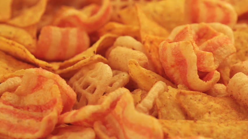 front view panning shot of a pile of different junk food types with different colors shapes and textures 