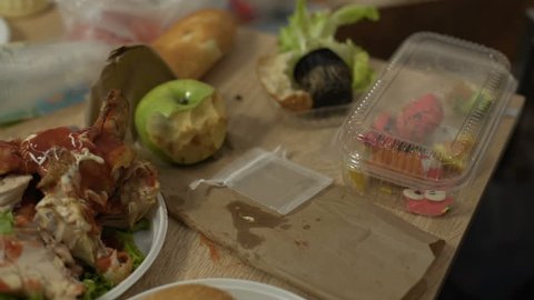 Messy tables full of unhealthy food leftovers after student party in empty room