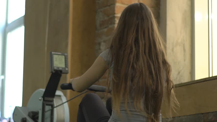 Slow Motion A Woman Working Out And Doing The Rowing Machine At The Gym