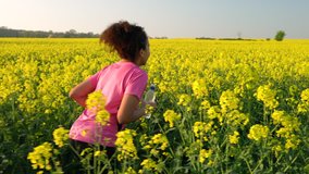 4K video clip of beautiful healthy mixed race African American girl teenager female young woman running or jogging with a bottle of water in field of yellow flowers
