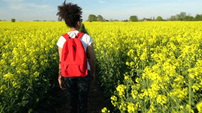 4K video clip of beautiful happy mixed race African American girl teenager female young woman hiking with red backpack yellow flowers