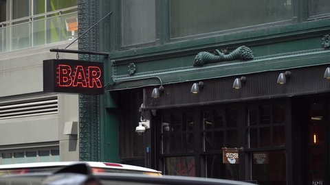 New York City Day time DX Establishing Shot of generic Bar Pub. Night exterior 4K video footage of vintage neon sign above tavern entrance. New York people go out at night to have fun, drink alcohol