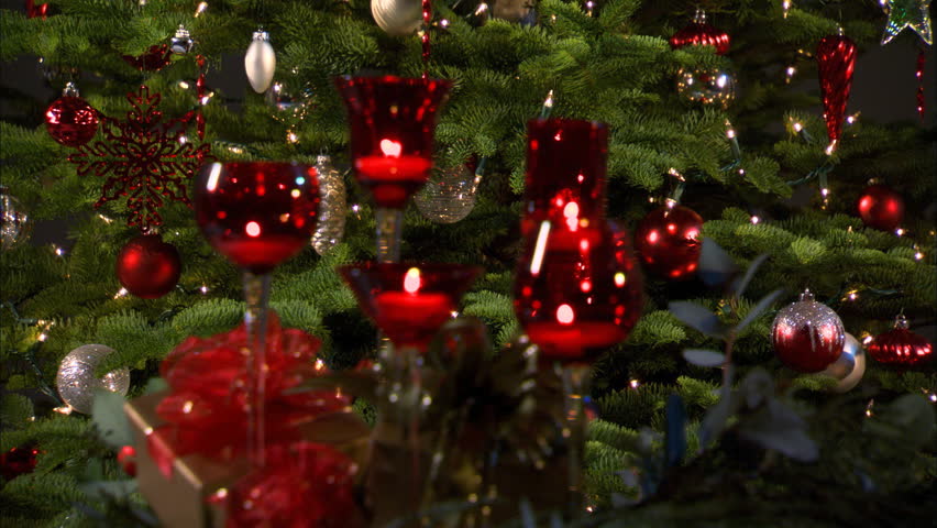 Rack-focus twinkling tea lights in red stemmed glasses in front of a Christmas tree | Shutterstock HD Video #26694682