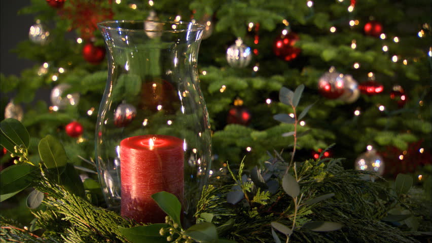 A red candle in a glass lantern chimney in front of a Christmas tree | Shutterstock HD Video #26694742