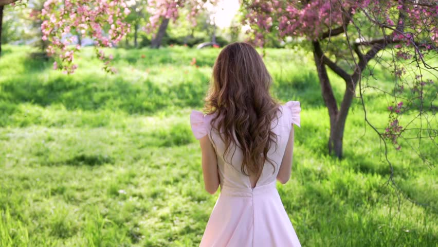 Smiling happy attractive woman goes among flowered garden and turns around Royalty-Free Stock Footage #26702281