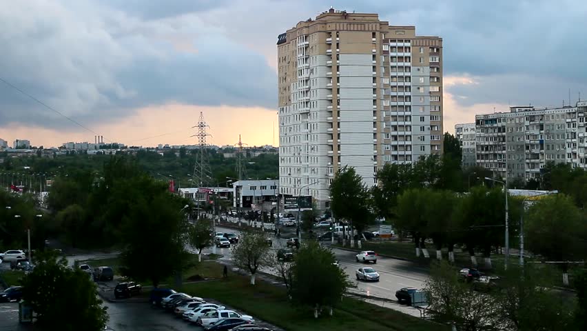 Urban buildings and moving cars on the road under a stormy cloudy sky