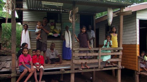Family posing for group portrait on porch of Fijian home