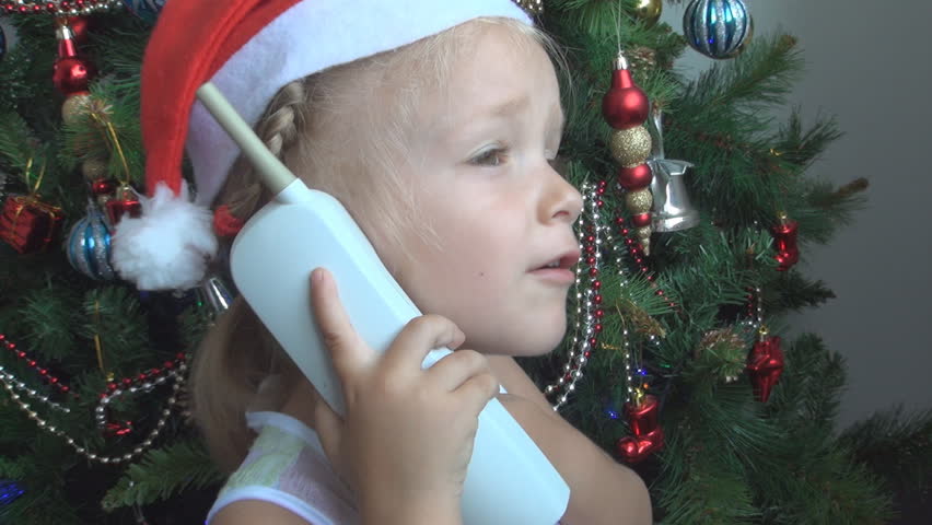 Child Smiling while Talking on the Phone with Santa Claus by the Christmas Tree