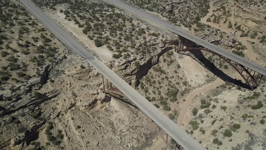 Aerial overhead circle Eagle Canyon Bridge highway desert landscape. Double span interstate I-70 highway crosses deep gorge. Travel traffic overhead drone. San Rafael Reef is a geologic landscape.