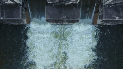 Aerial view of water rushing through the gates at a dam.