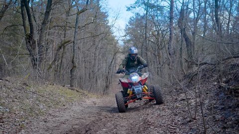 Autumn forest. The man in a special form on the ATV. The racer rides on the wood the racing ATV.