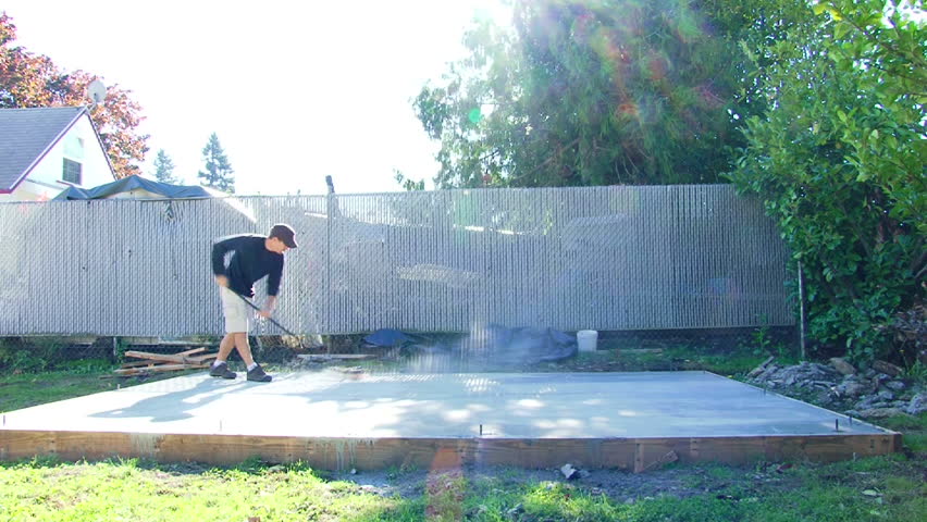 Model released man sweeping off dust from new concrete foundation, time lapse.