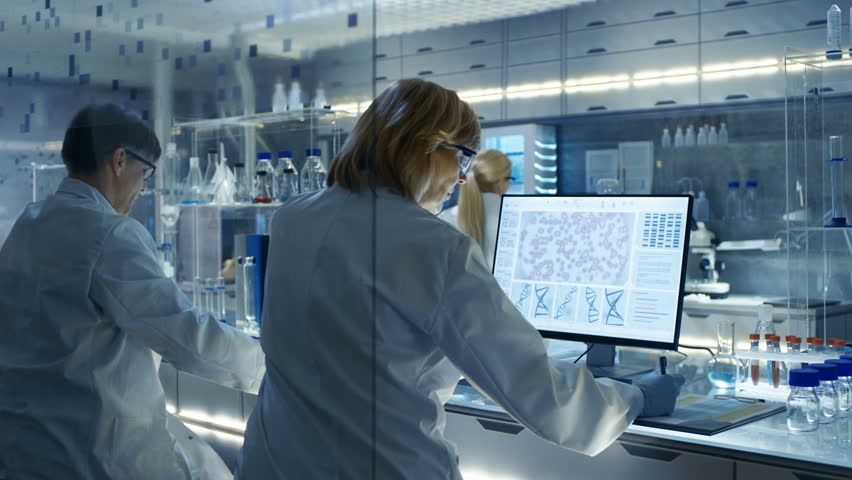 Female and Male Scientists Working on their Computers In Big Modern Laboratory. Various Shelves with Beakers, Chemicals and Different Technical Equipment is Visible.Shot on RED EPIC-W 8K Helium Camera - Powered by Shutterstock - Get 15% off with code: PIKWIZARD15