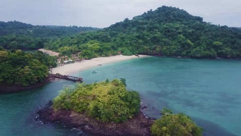 Aerial approaching a tropical beach with boat in Coiba with pier, Panama