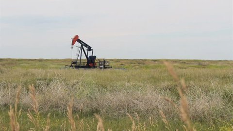 A lonely oil pump works endlessly in the middle of the barren Canadian prairies.