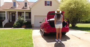 Drone video 4K 60 fps.Woman opens cars door,takes groceries from trunk and comes to house.Girl after shopping in  store returning home and goes out red car.Suburb building located in green subdivision